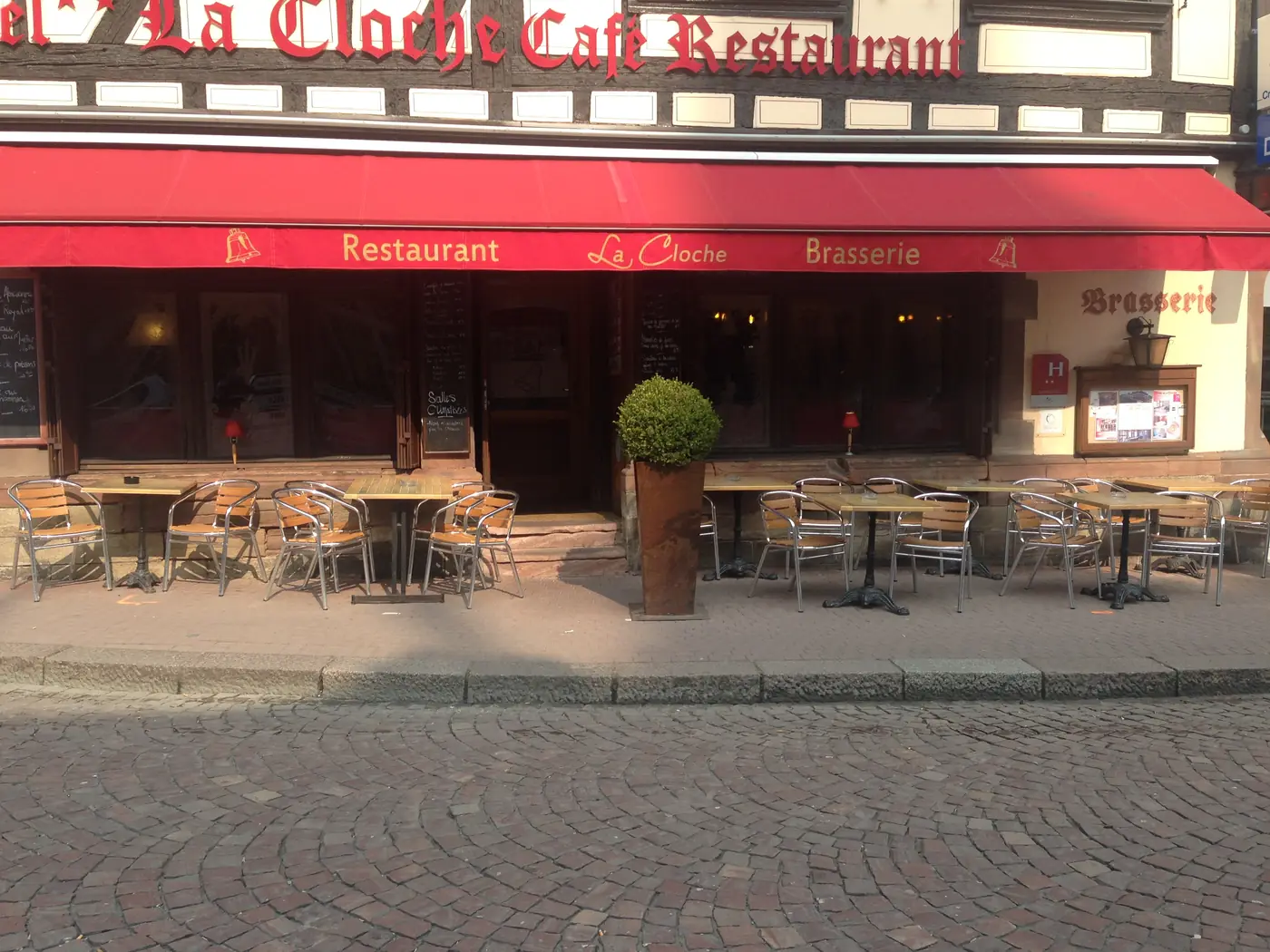 La terrasse de La Cloche sous l’auvent rouge, rue du Général Gouraud