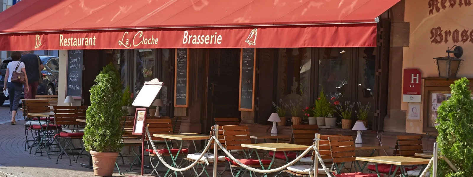 La terrasse de La Cloche, rue piétonne, sous l’auvent rouge